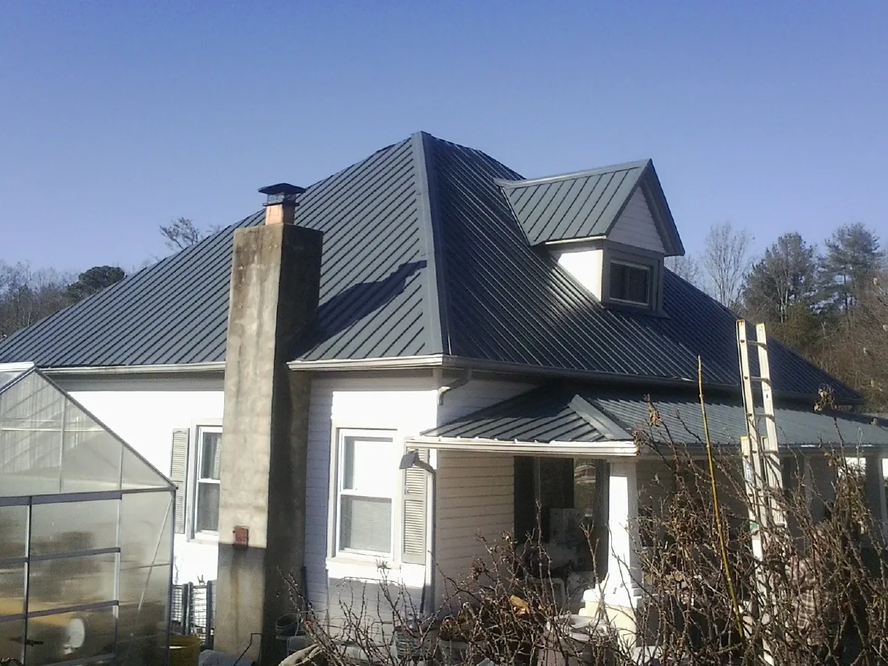 Dark blue standing seam metal roof on a white farmhouse with dormer — Slate & Tile Roof Repair by Roofing Brothers in Sloughhouse