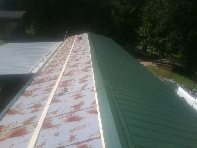 Old rusted panels beside newly installed green metal roofing — Wind Damage Roof Repair by Roofing Brothers in Sloughhouse