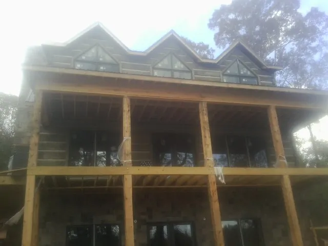 Dormers and porch framing on a large log home under construction — Roof Coating work by our crew in Sloughhouse