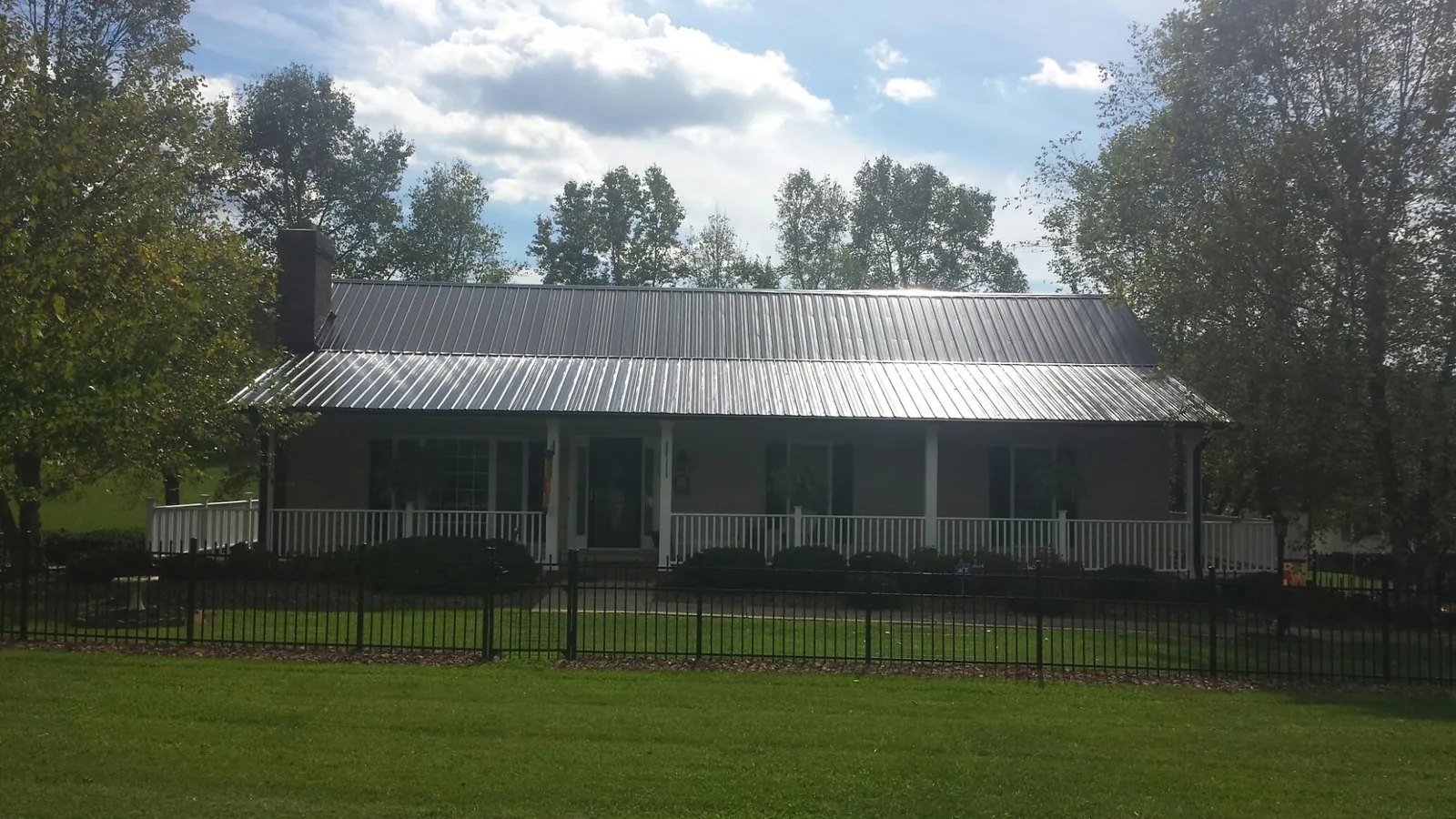 Gray metal roof on a brick ranch with a full width front porch — Gutter Guard Installation work by our crew in Sloughhouse
