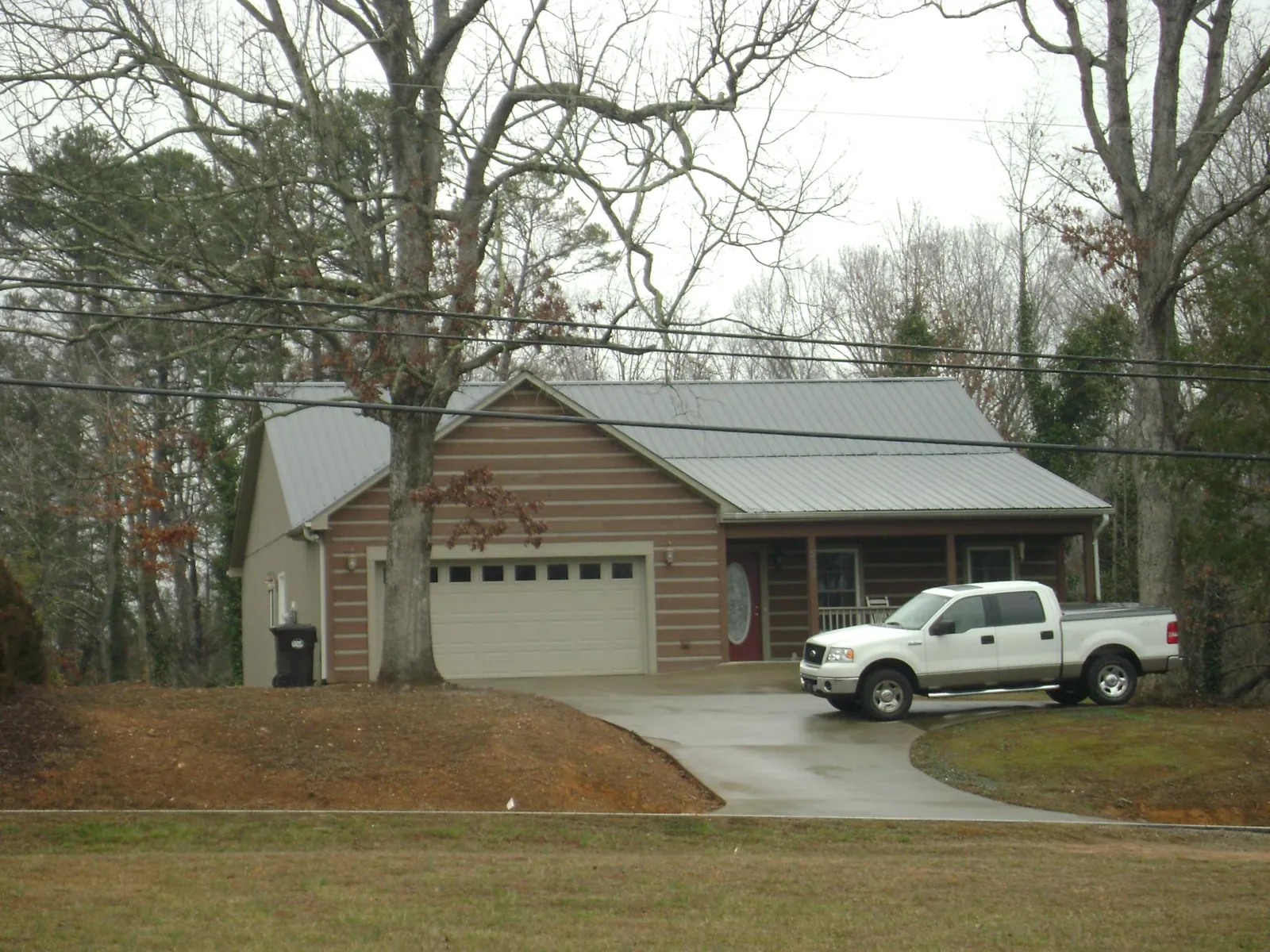 Gray metal roof on a log sided house with an attached two car garage in Sloughhouse
