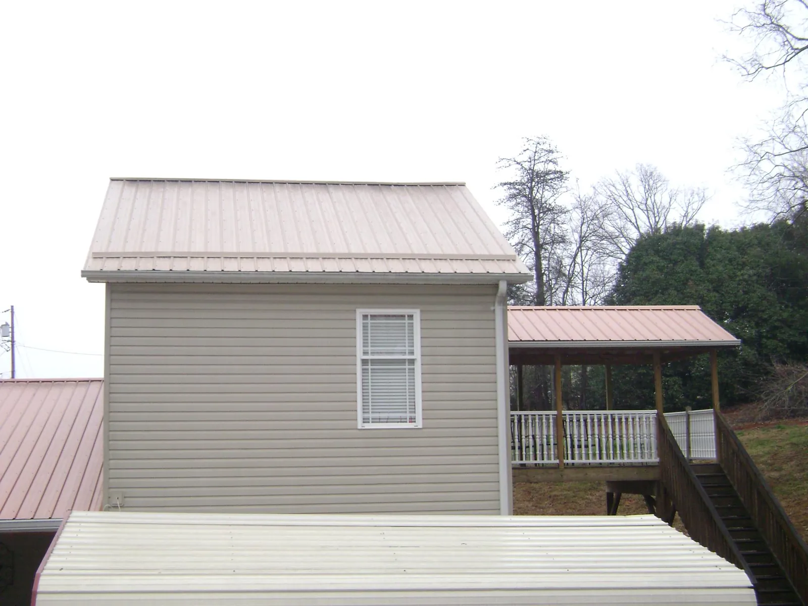 Tan metal roofs on a two story addition and attached porch, from a Roof Replacement job in Sloughhouse