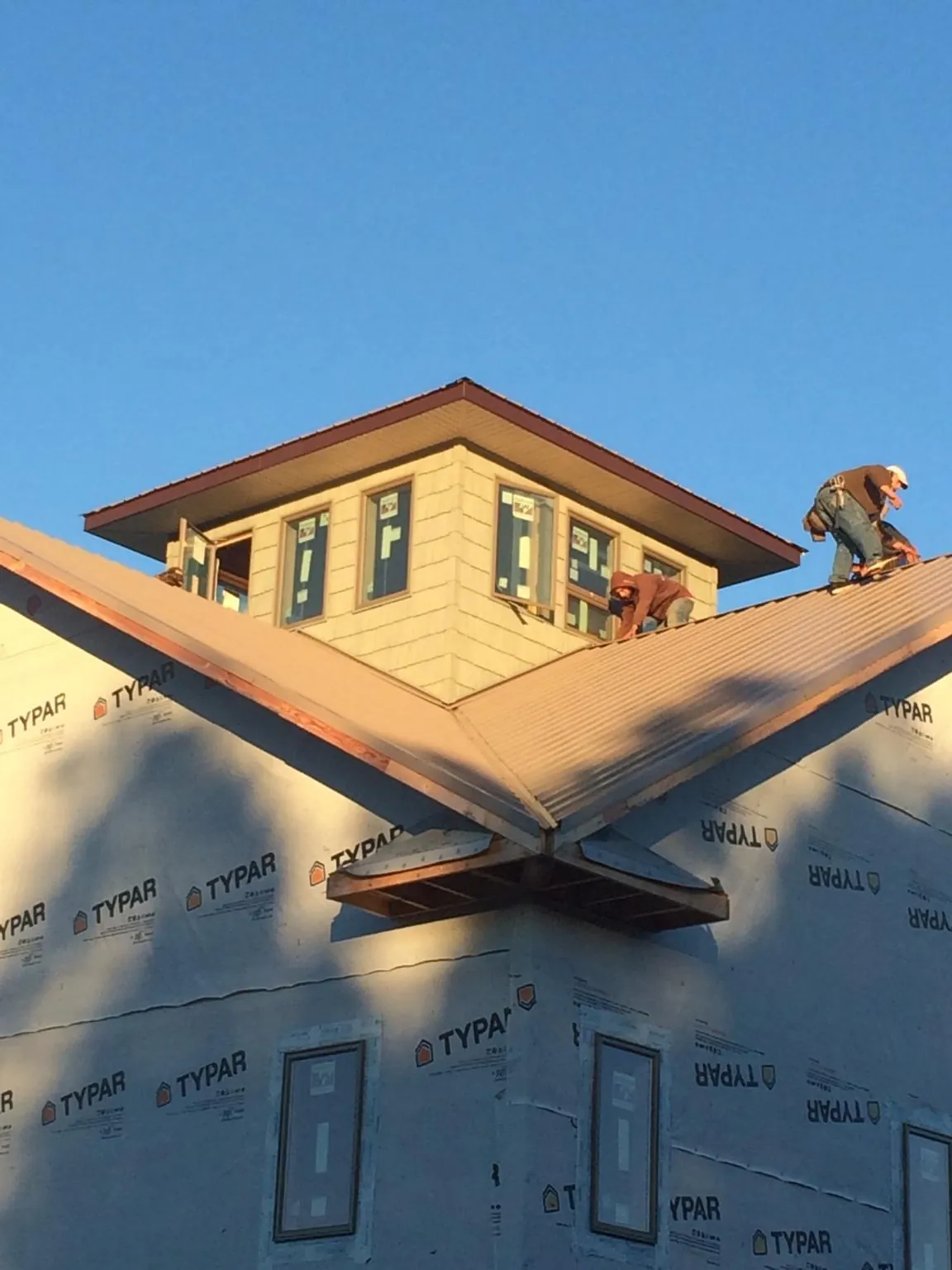 Roofers working around a rooftop cupola on a new metal roof at sunset — Roof Waterproofing in Sloughhouse by Roofing Brothers